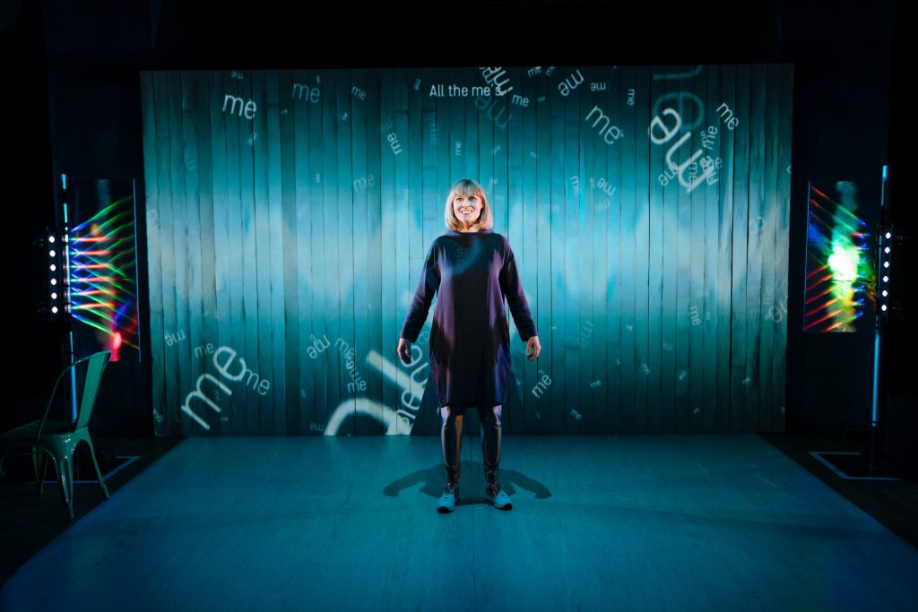 Sophie looks euphoric on a stage surrounded by projected text that says me me me me me